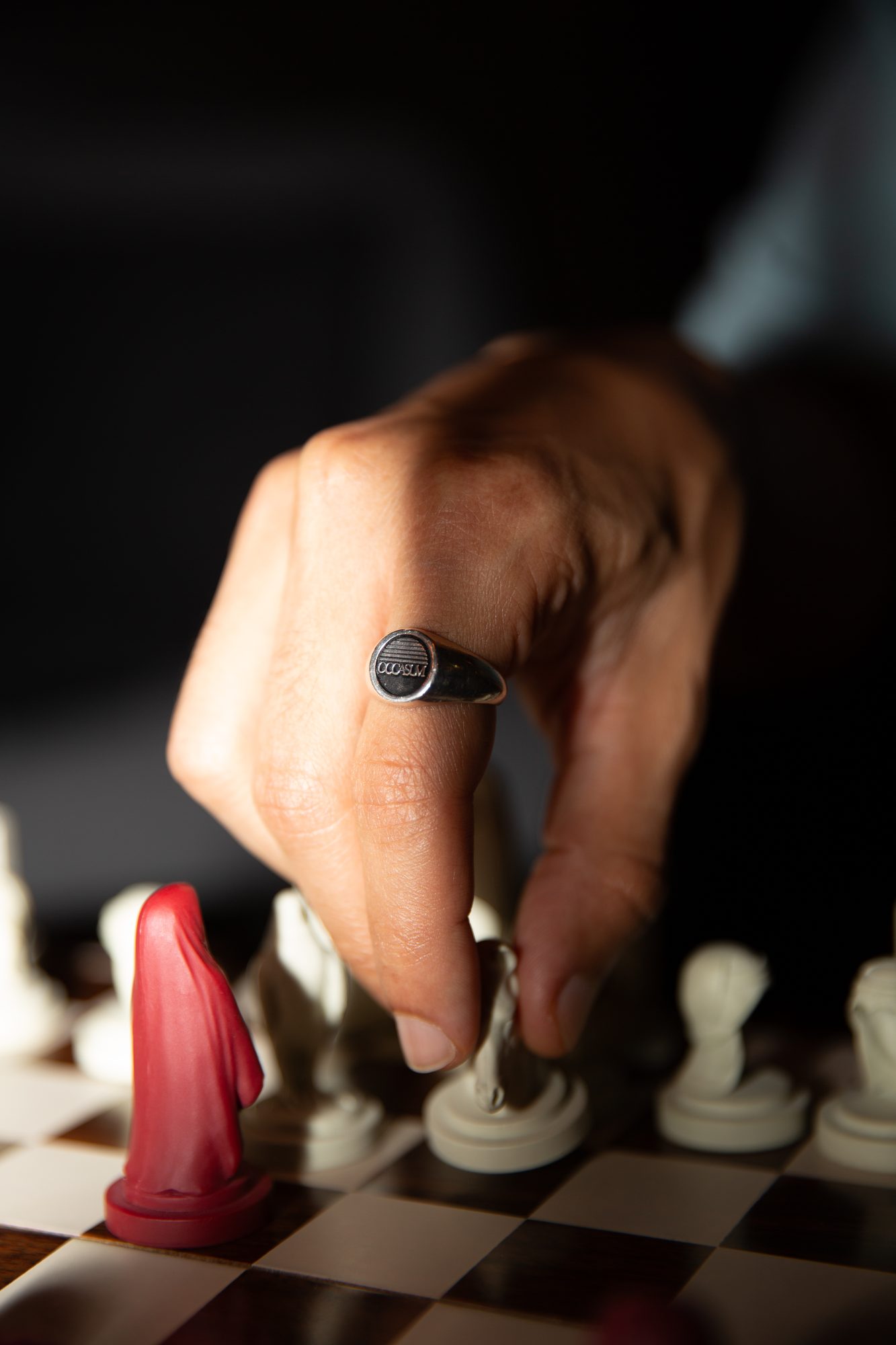 Hand with a signet ring moving a chess piece