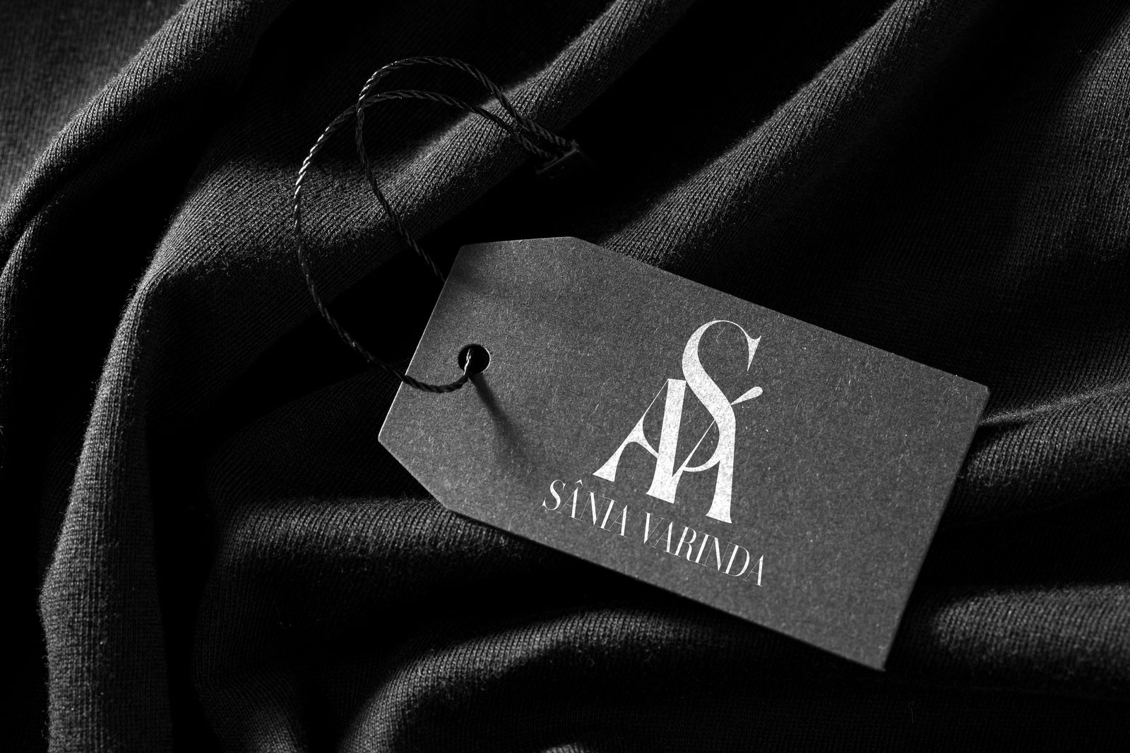 Grey SÁVA swing tag on black fabric